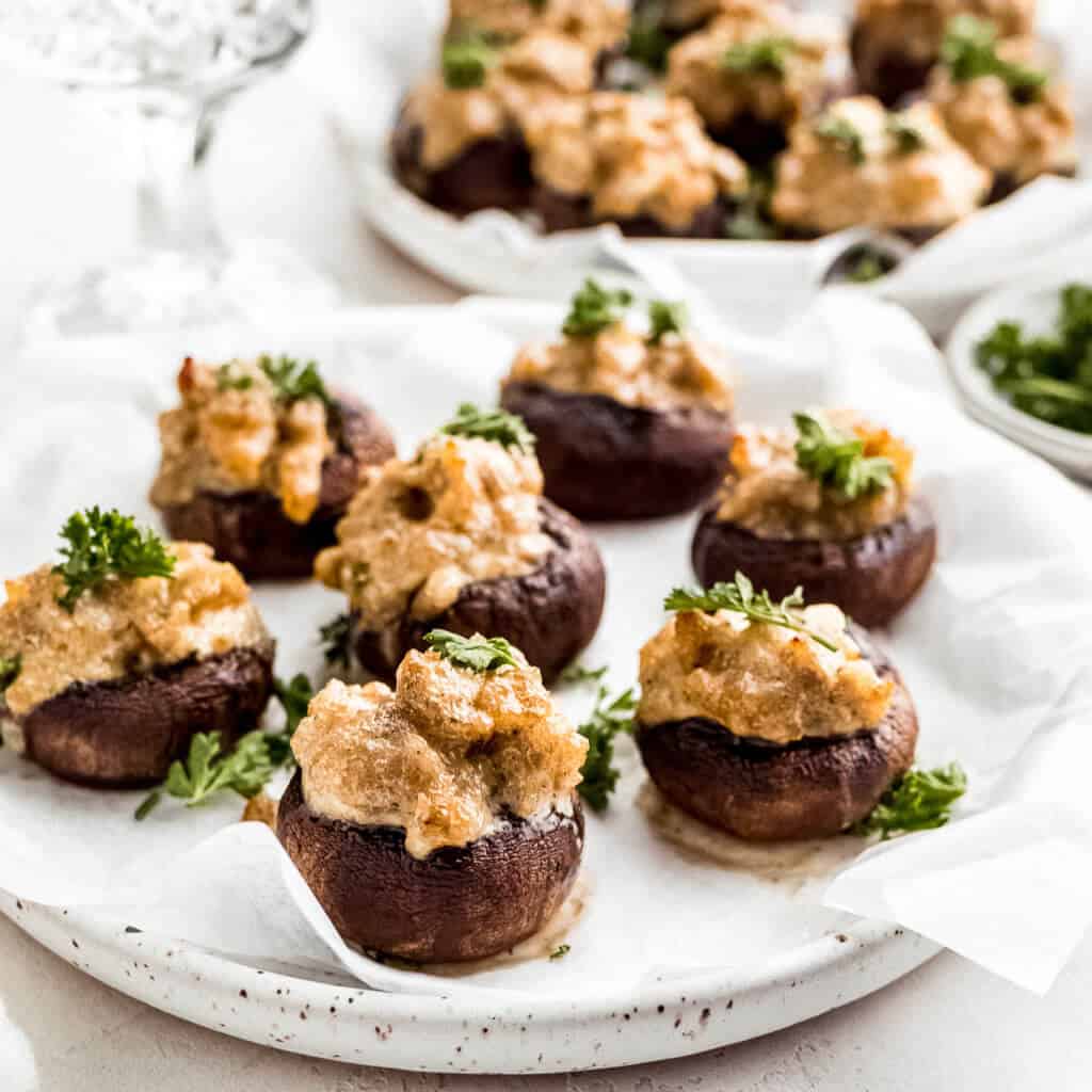 A plate filled with mushrooms that are stuffed with creamy sausage stuffing