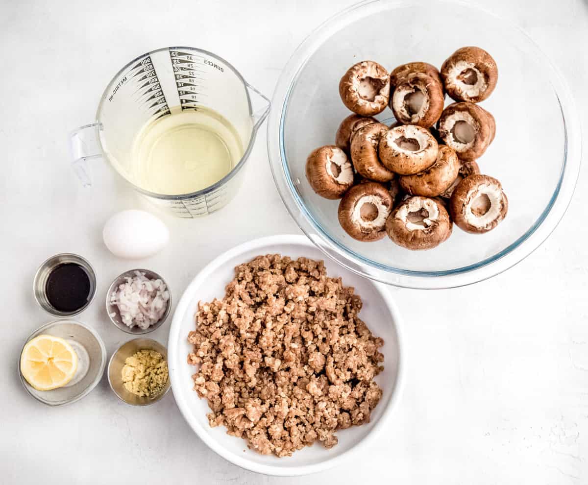 Keto stuffed mushroom recipe ingredients laid out on a white countertop.