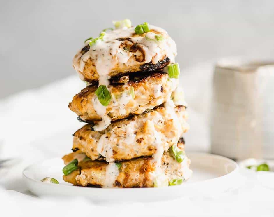 a large stack of chicken patties with spicy ranch drizzled over the top. 