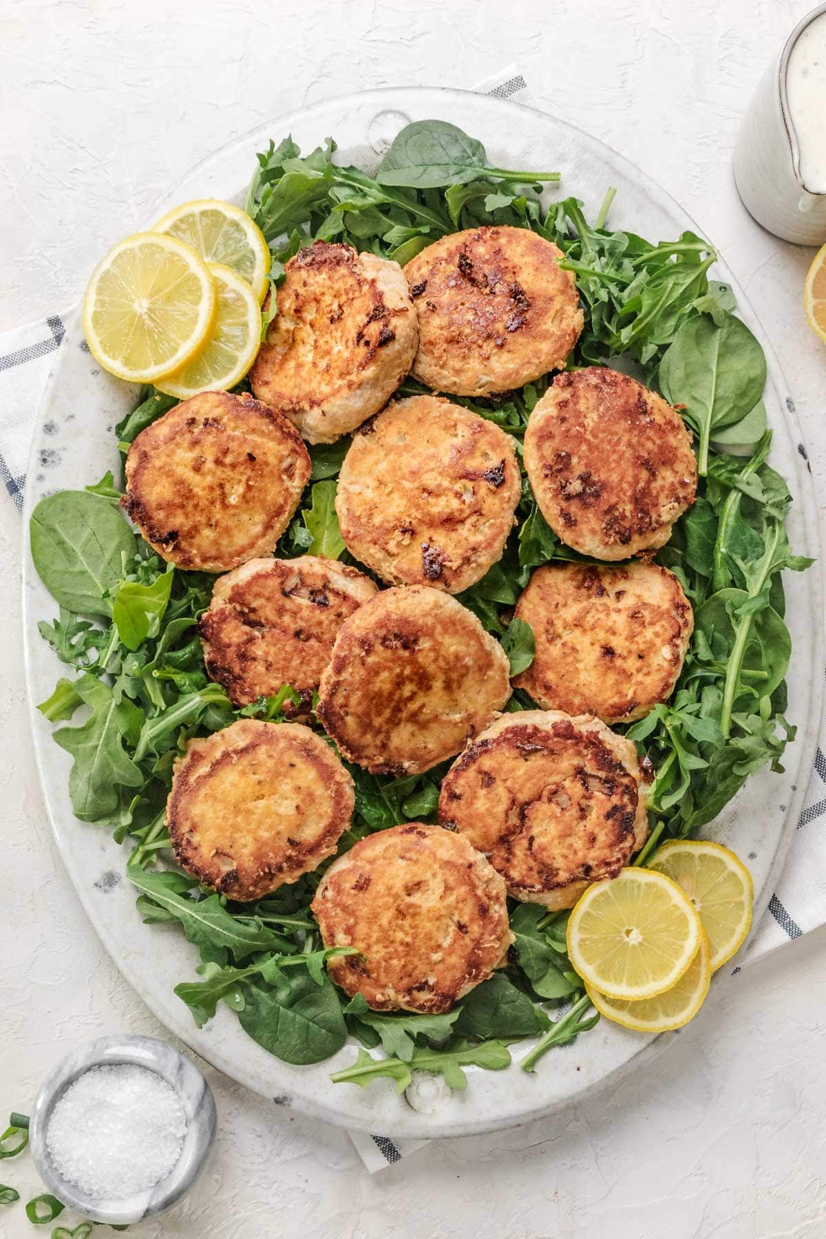 air fryer chicken patties served over a bed of lettuce with sliced lemons on the side