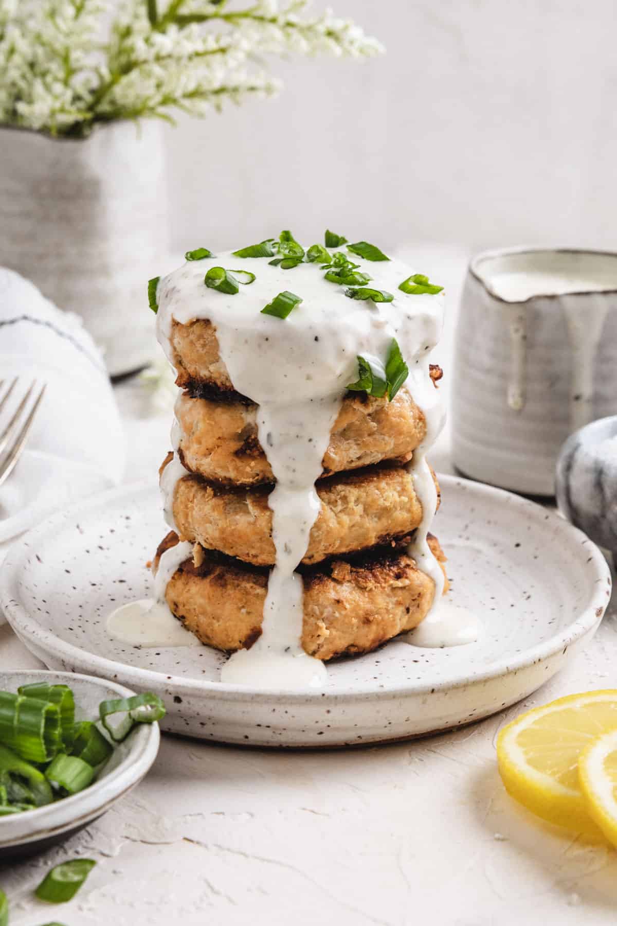 four air fryer chicken patties stacked on top of each other with ranch poured over the top