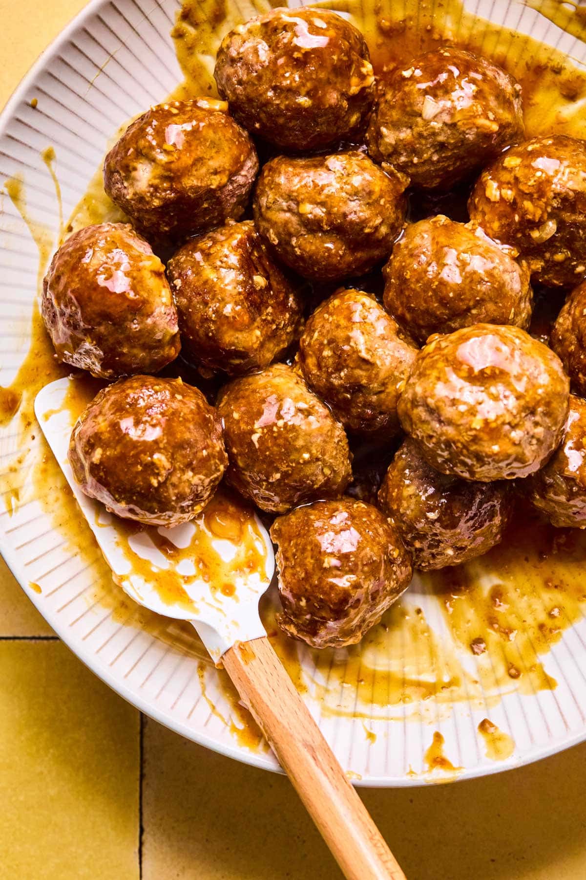 Asian meatballs on a plate coated in sticky sauce.