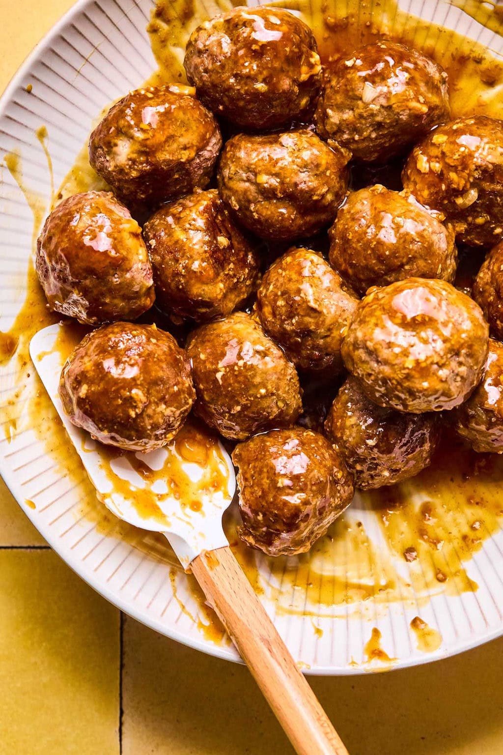 Asian meatballs on a plate coated in sticky sauce.