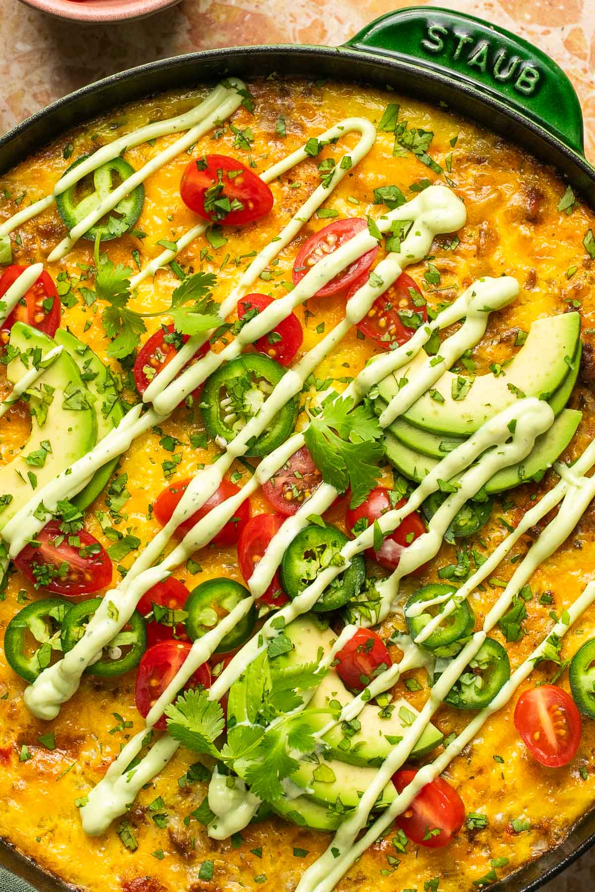 an up close shot of a frittata drizzled with avocado ranch dressing