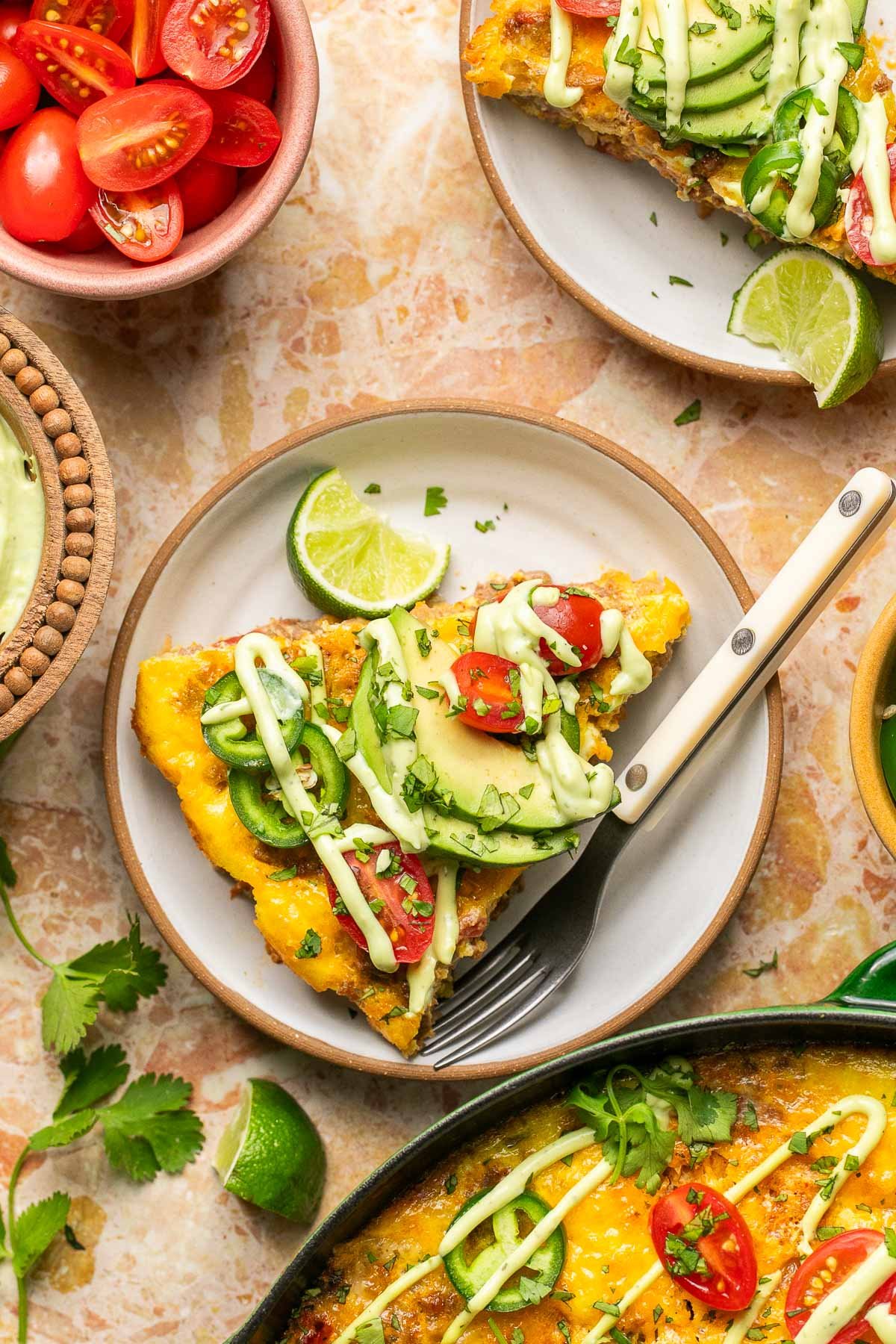 a slice of Mexican frittata on a plate with toppings and avocado ranch. 