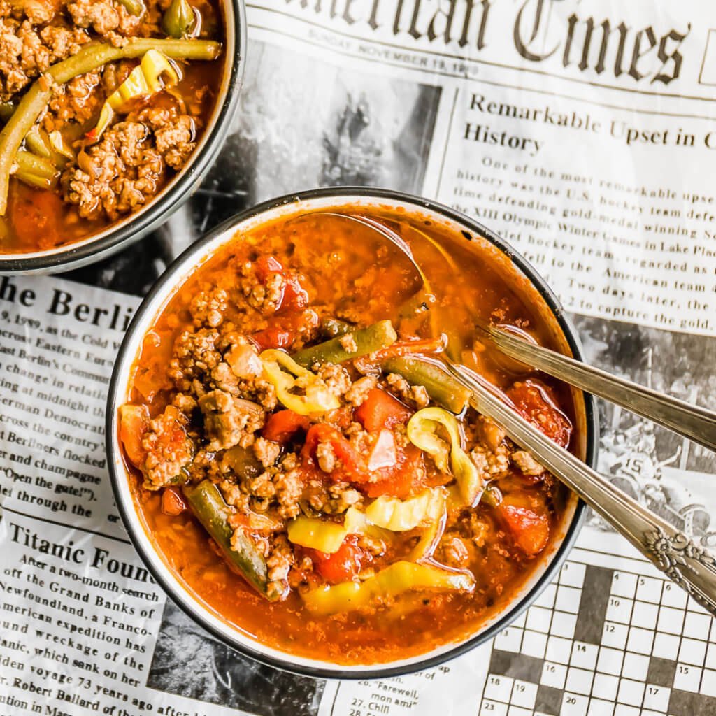 dairy free hamburger soup in a bowl with two spoons on top of a newspaper