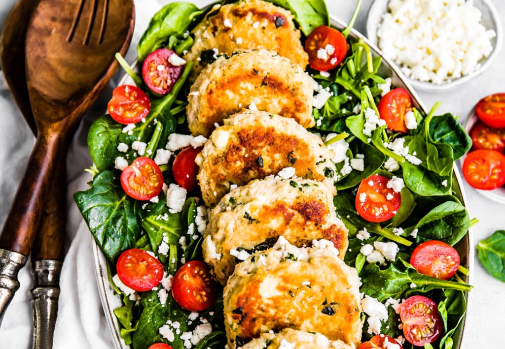 Feta and Spinach Chicken Patties on top of a spinach salad