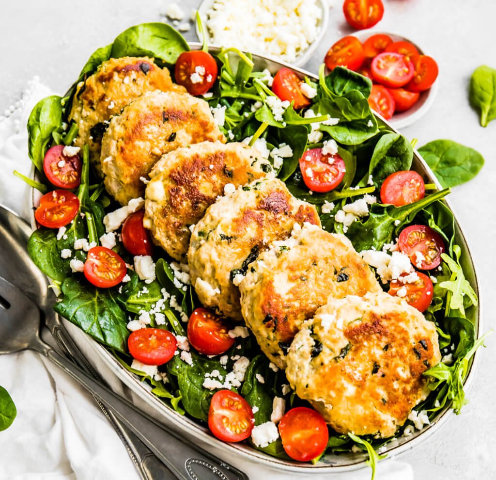 Feta and Spinach Chicken Burgers on top of a spinach salad