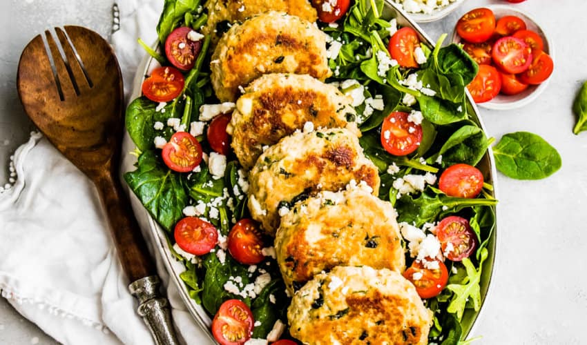 Feta and Spinach Chicken Burgers on top of a spinach salad