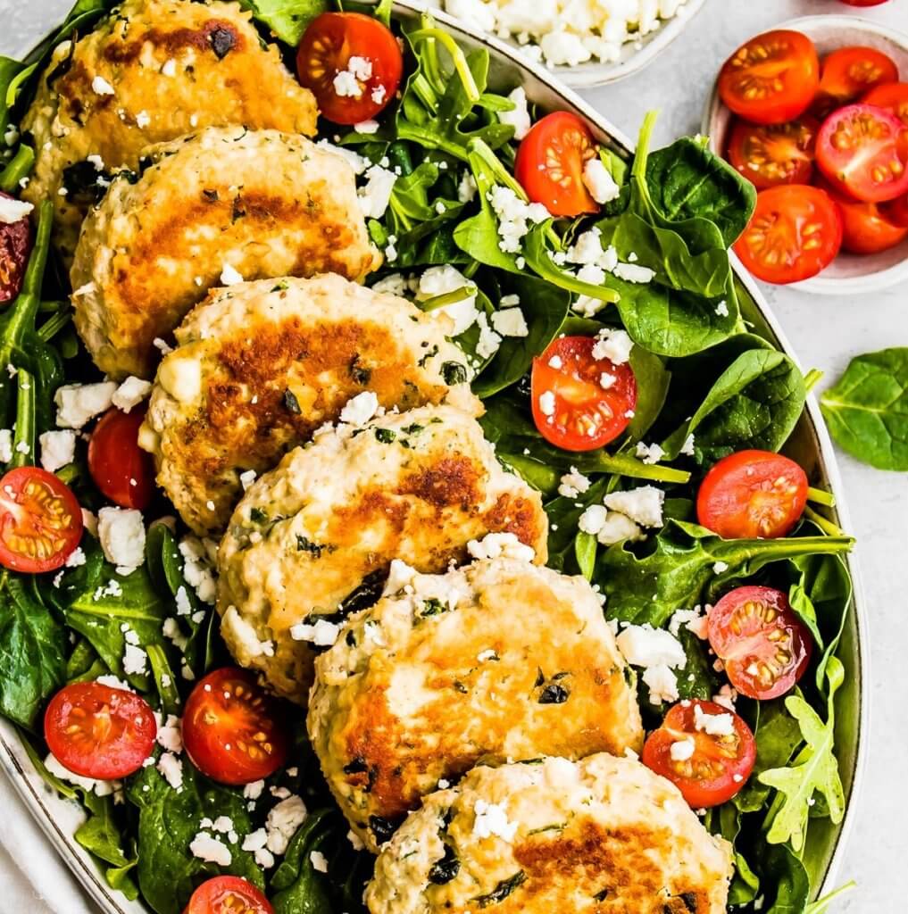 Feta and Spinach Chicken Patties on top of a spinach salad