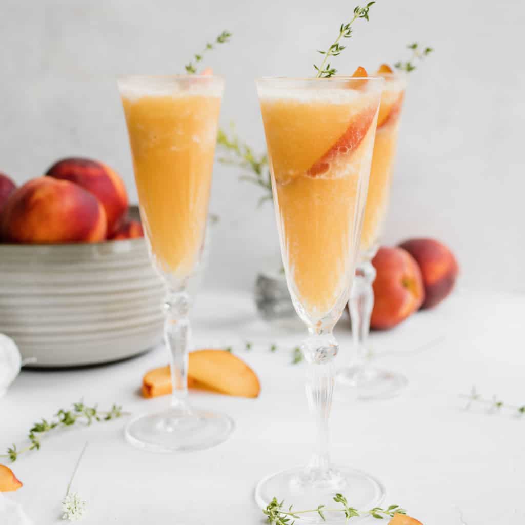 Peach Wine Slush with thyme as garnish and a fresh peach slice
