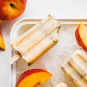 Peach Crisp Popsicles on ice with sliced peaches
