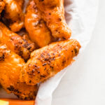 A close up picture of a chicken wing tossed in buffalo sauce.