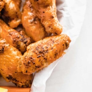 A close up picture of a chicken wing tossed in buffalo sauce.