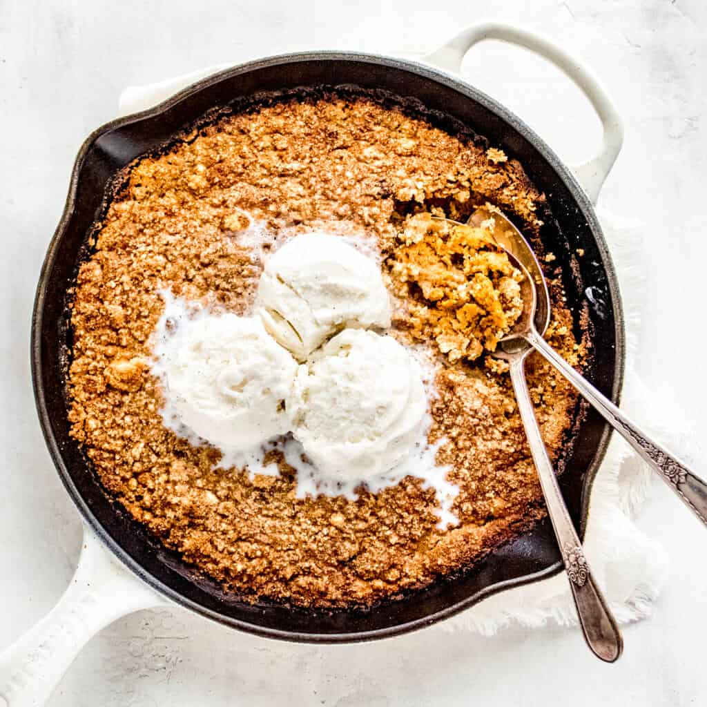 Pumpkin crisp with two spoons and vanilla ice cream