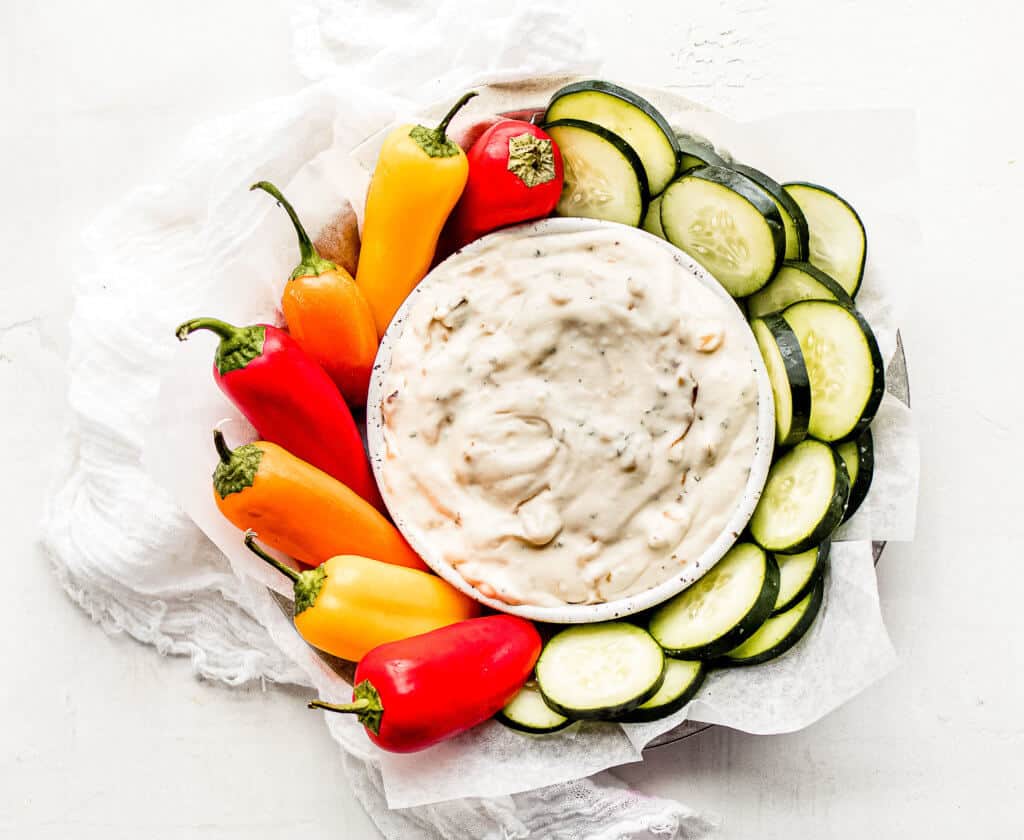 A overhead shot of the onion dip and cucumbers and mini peppers