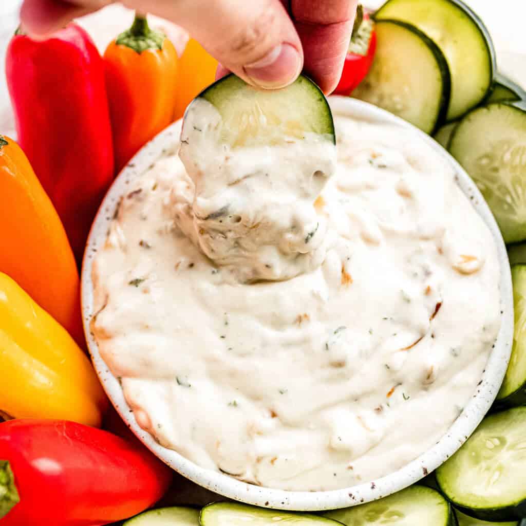 A cucumber being dipped into the dip