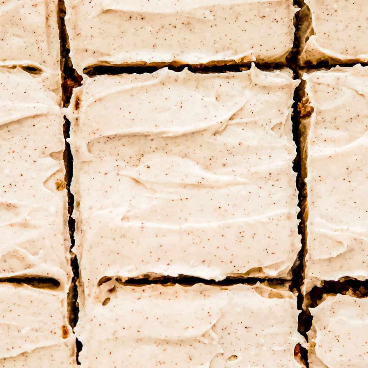 a row of keto carrot cake bars frosted with cinnamon cream cheese frosting