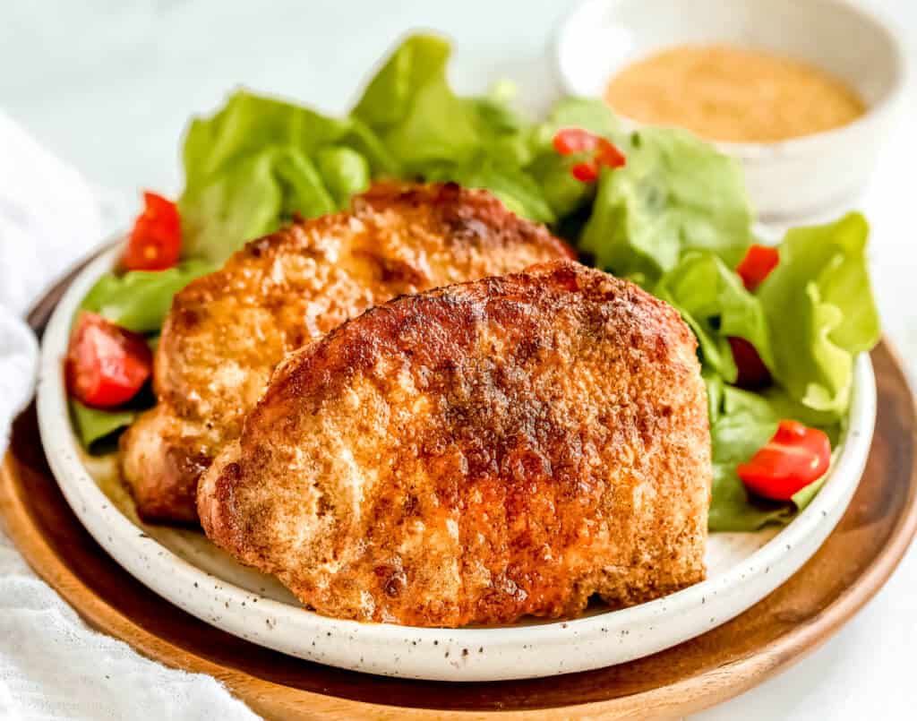 Air Fryer Buffalo Pork Chops on a bed of green lettuce and tomatoes