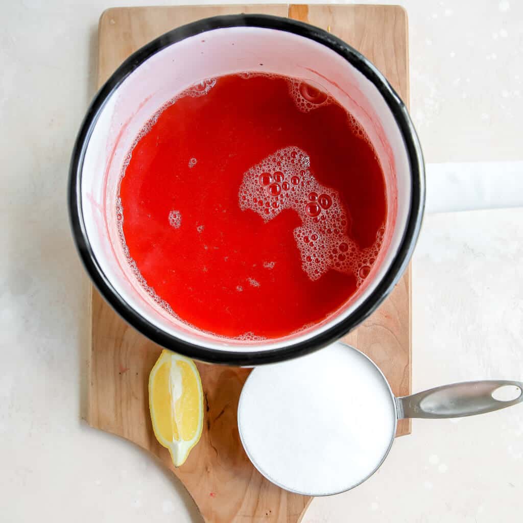 strawberry sauce in a pot with monk fruit and lemon slice around it
