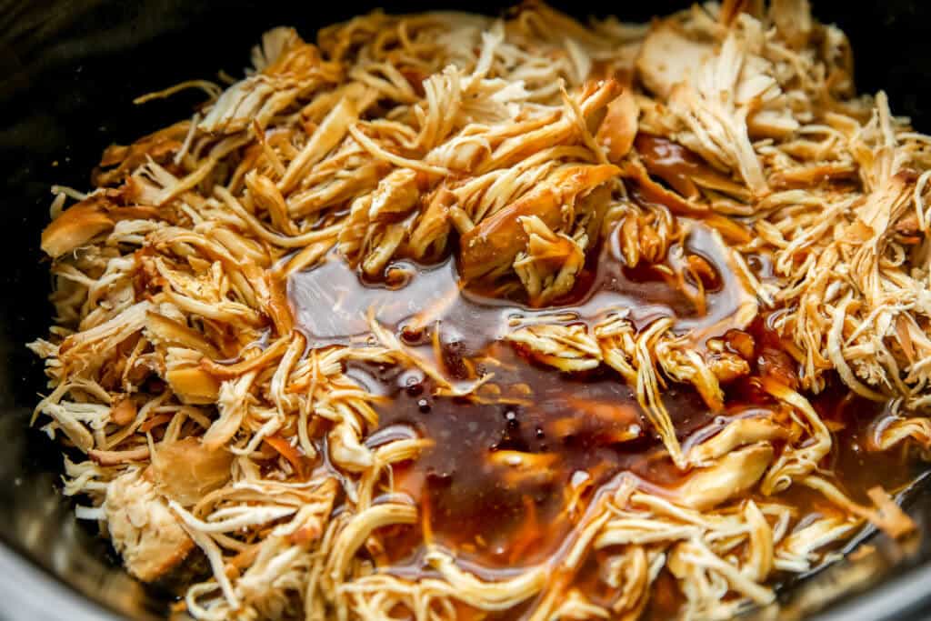 Shredded chicken in crockpot with teriyaki sauce poured over the top
