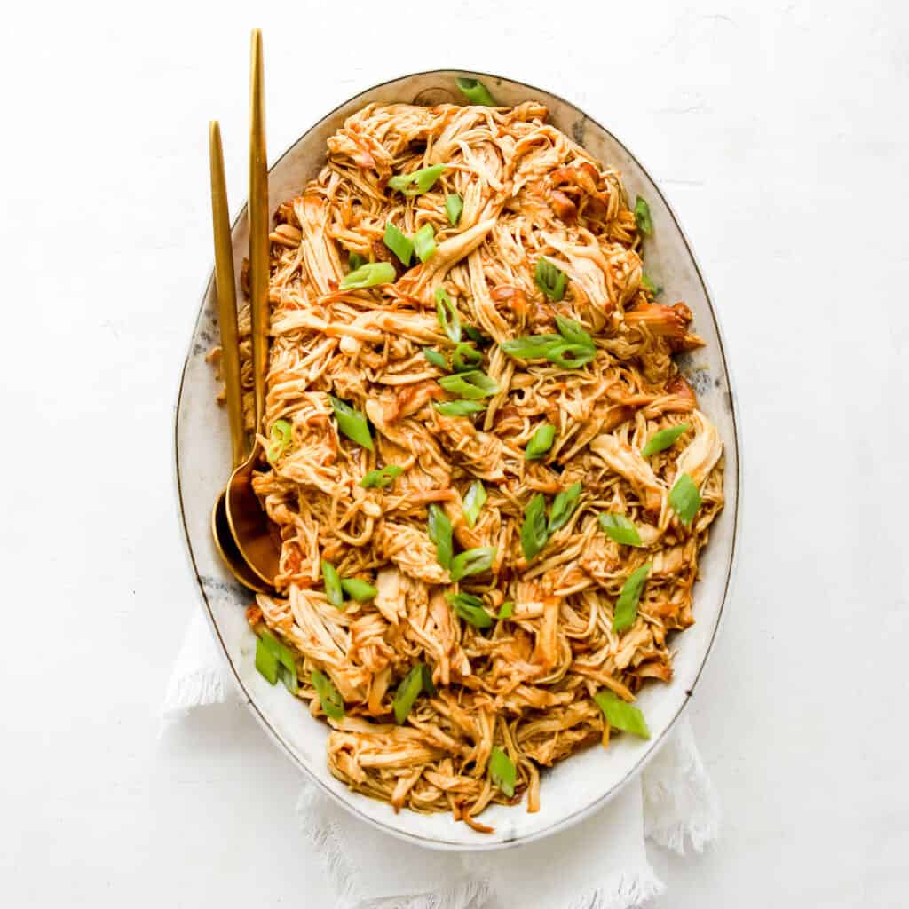 Keto Shredded Chicken Teriyaki with green onions in a platter with a serving spoon