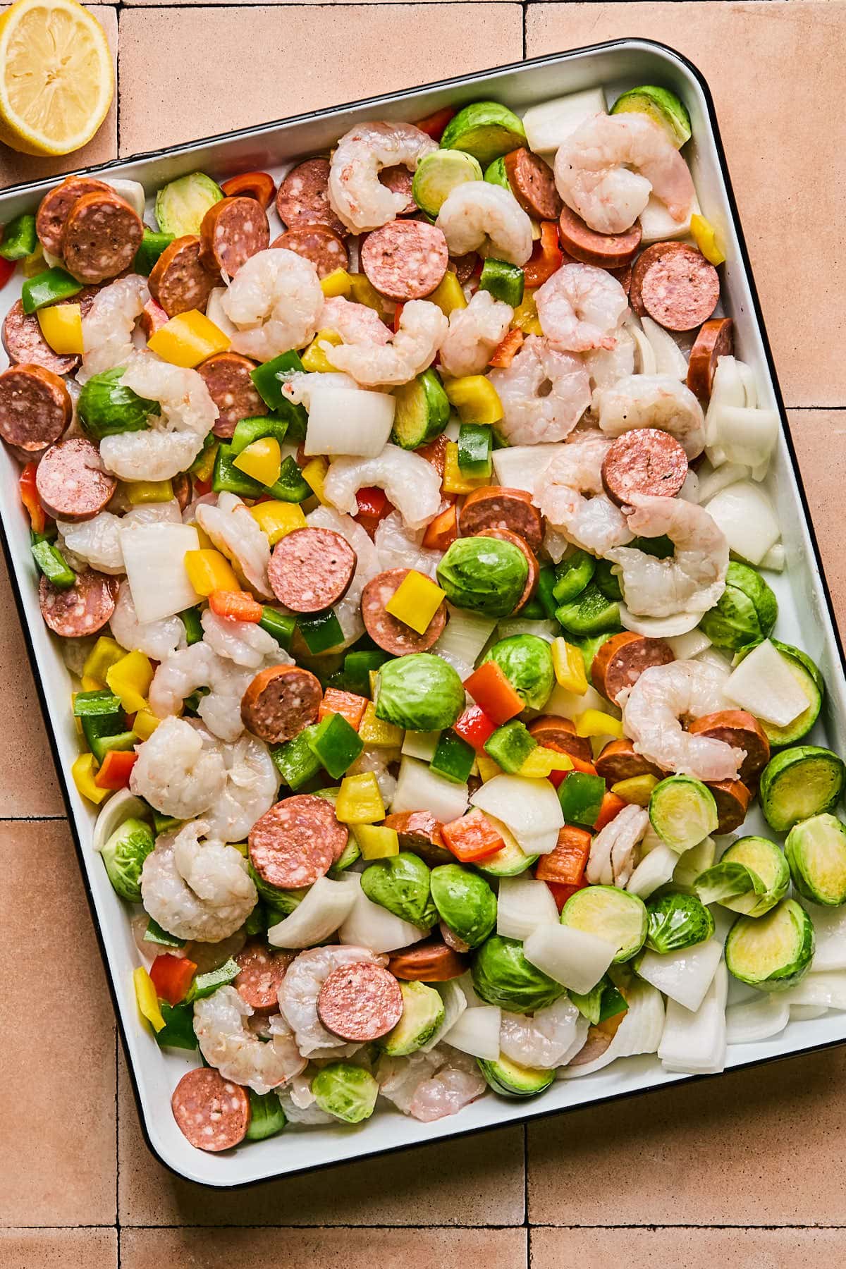raw veggies and sausage on a sheet pan