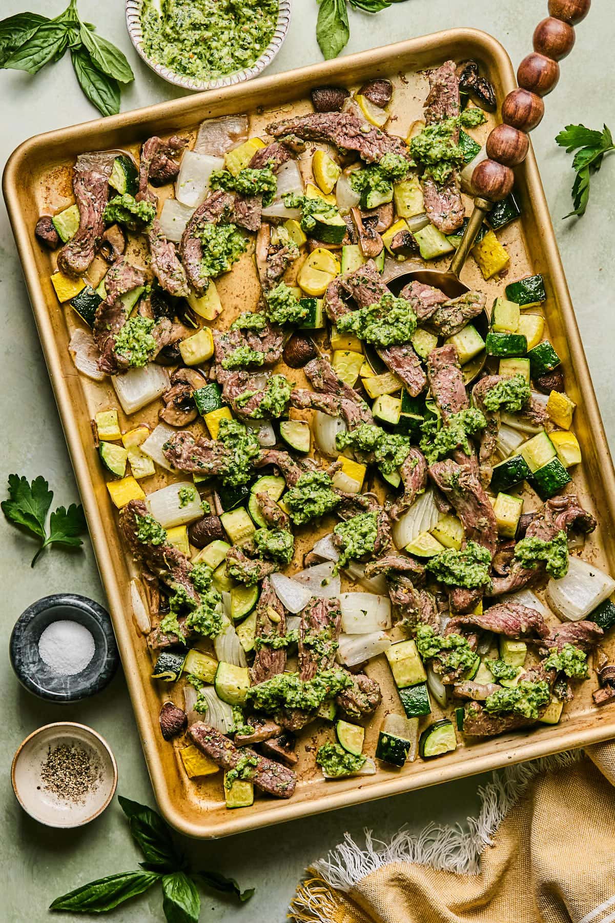 a sheet pan filled with steak and vegetables and covered in chimichurri sauce