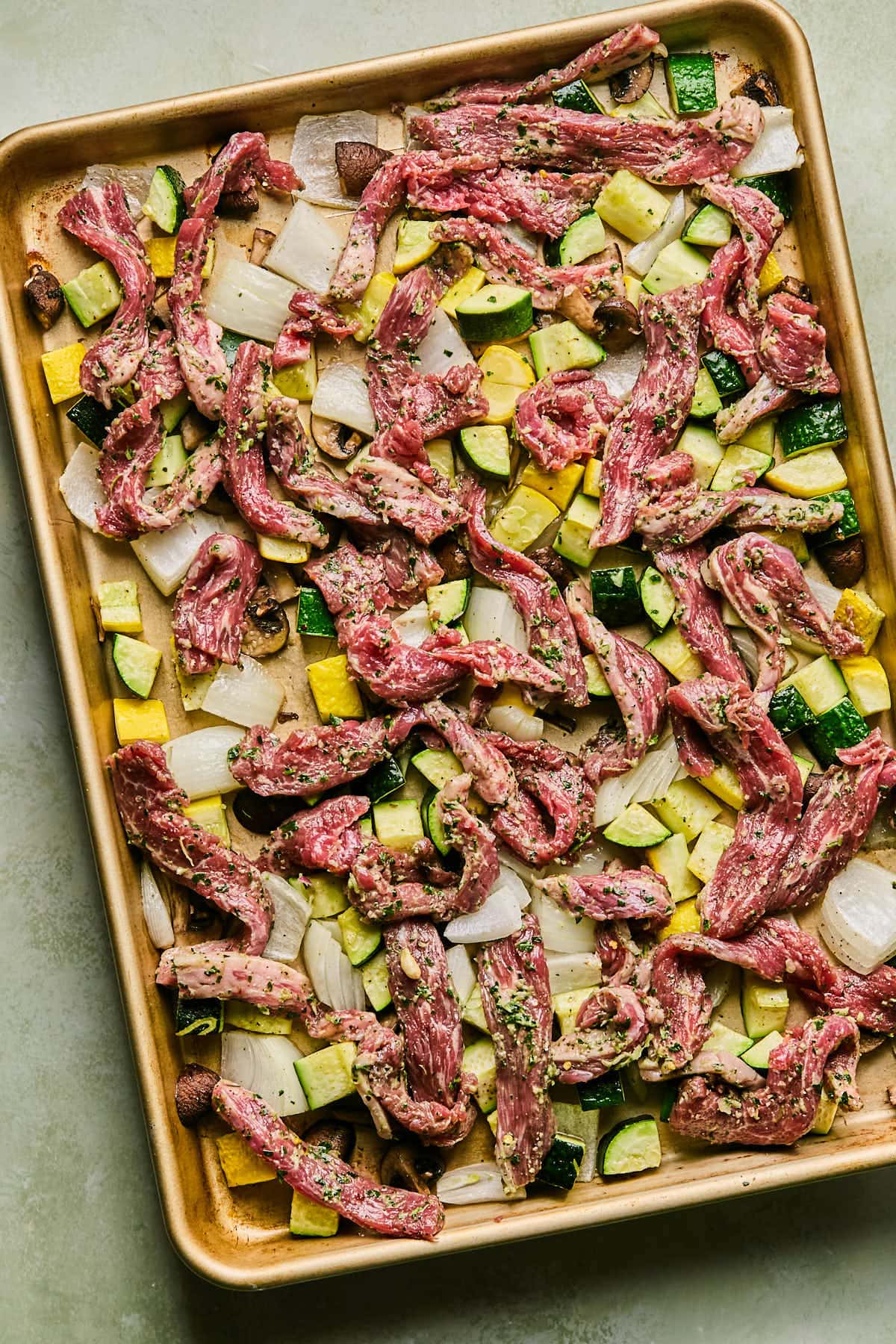 flank steak and chimichurri and veggies resting on a sheet pan 