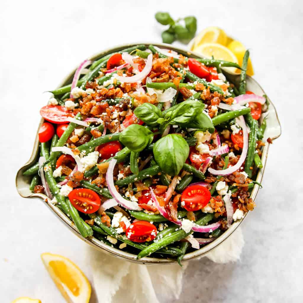 An overhead shot of the green bean salad with green beans, tomatoes, feta, red onion, lemon juice, olive oil and salt and pepper. 