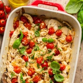 a casserole dish filled with chicken tomato bake with a wooden spoon resting on the side