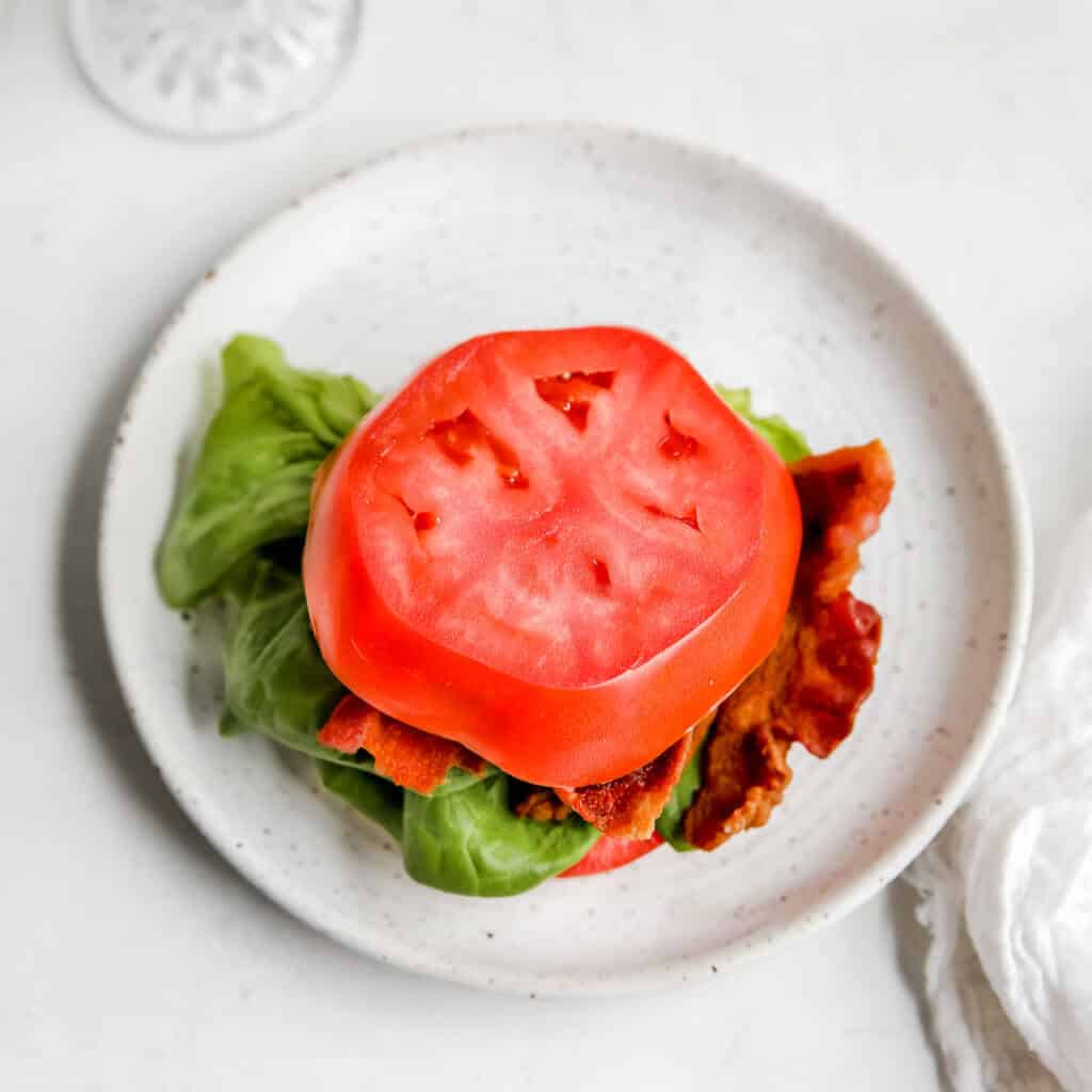overhead shot of a tomato bun blt on a plate 