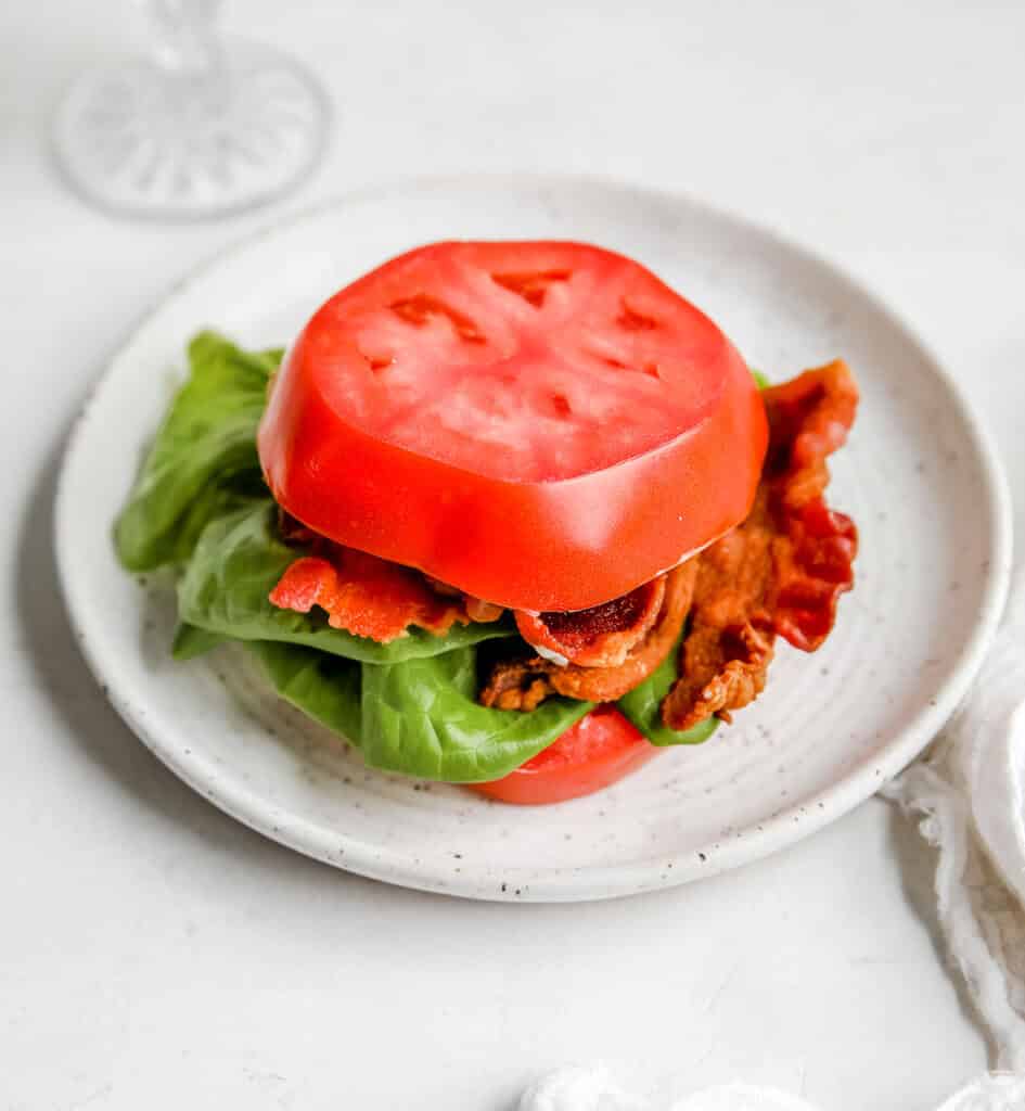 side shot of a tomato bun blt on a plate 