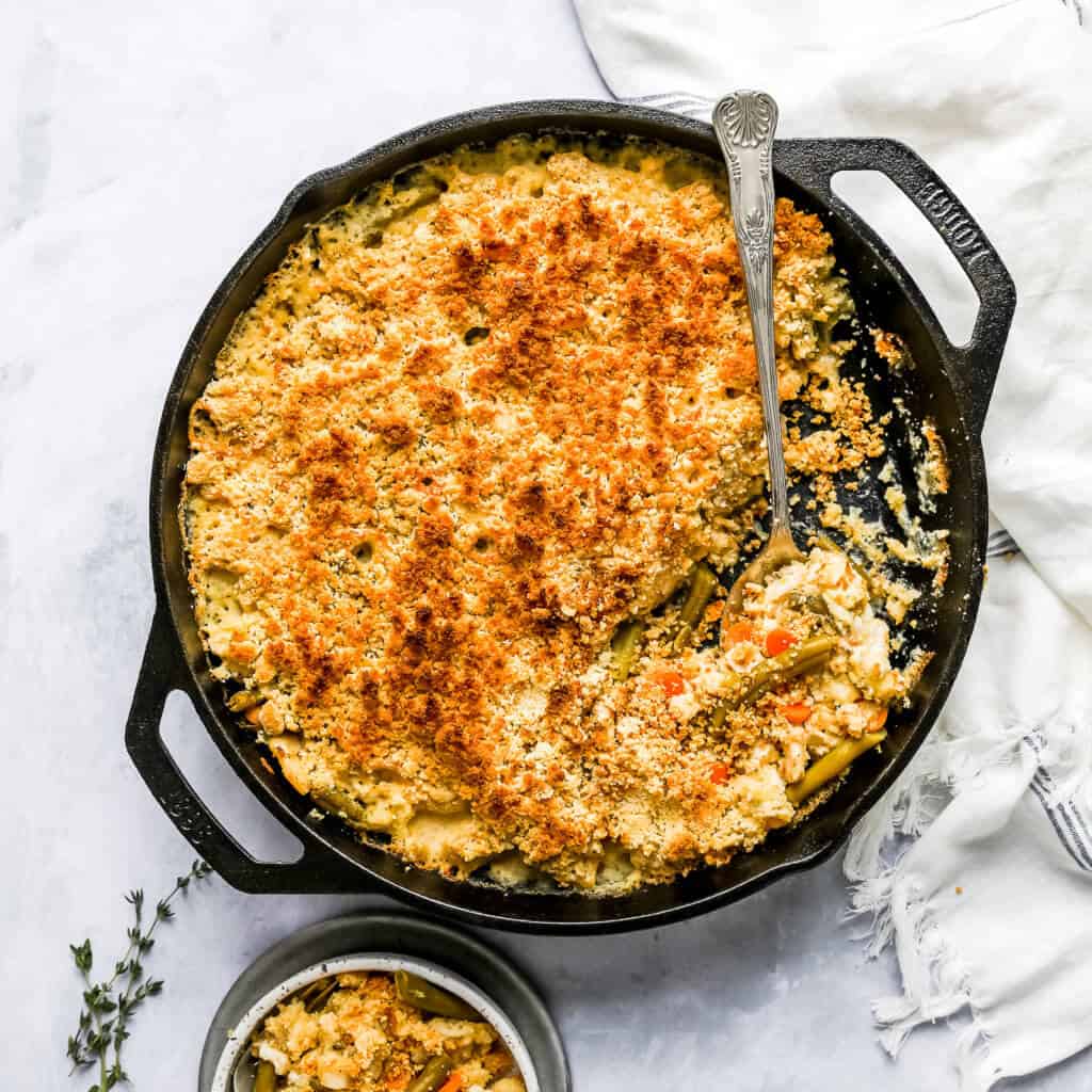 Chicken Pot Pie Casserole in a large cast iron skillet with a spoon and dish towel
