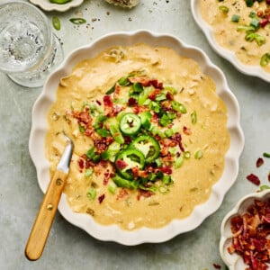 jalapeno popper soup in a white bowl with toppings