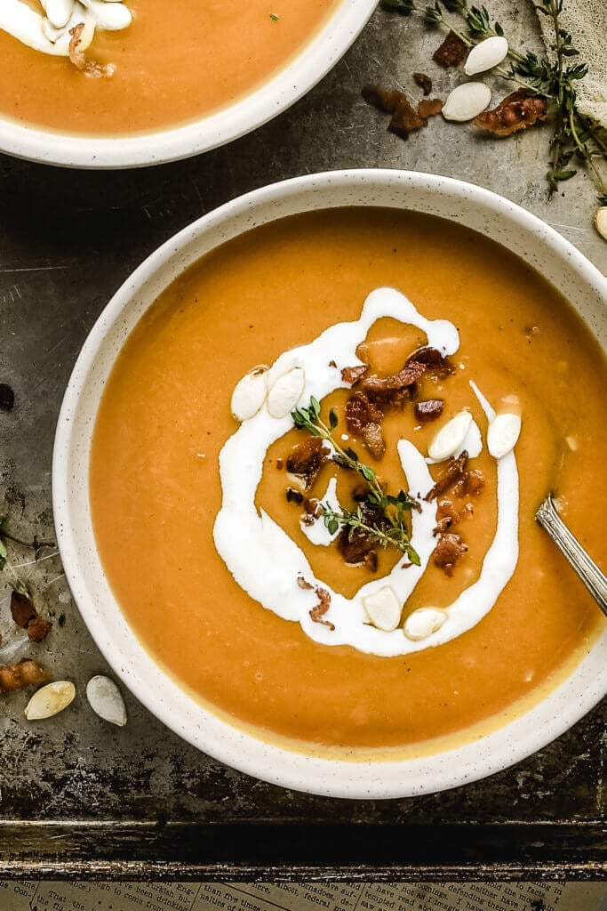close up of healthy butternut squash soup with bacon, coconut cream, and pumpkin seeds