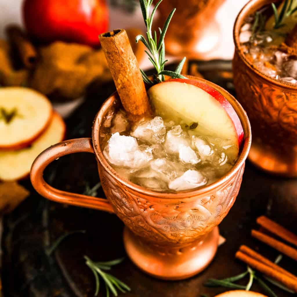 An overhead shot of a copper mug with apple cider and apple slices with ice