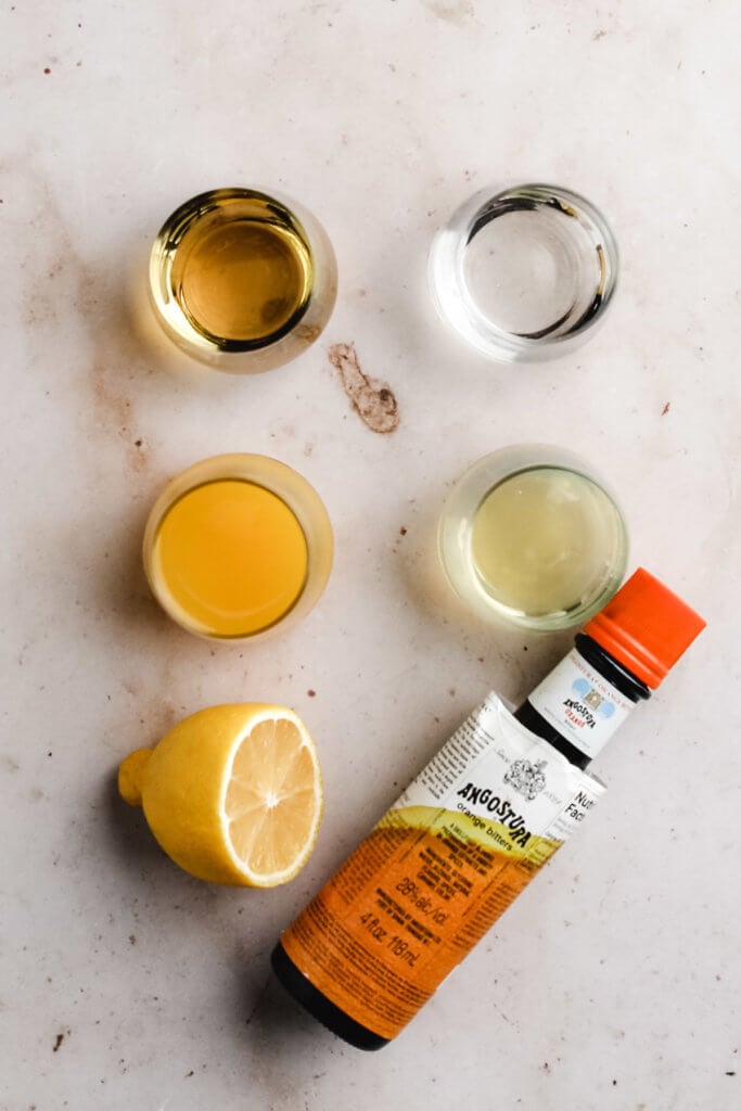 ingredients needed to make the ultimate whiskey sour cocktail, including bourbon, orange bitters, lemon juice, orange juice, simple syrup, grenadine, and egg whites