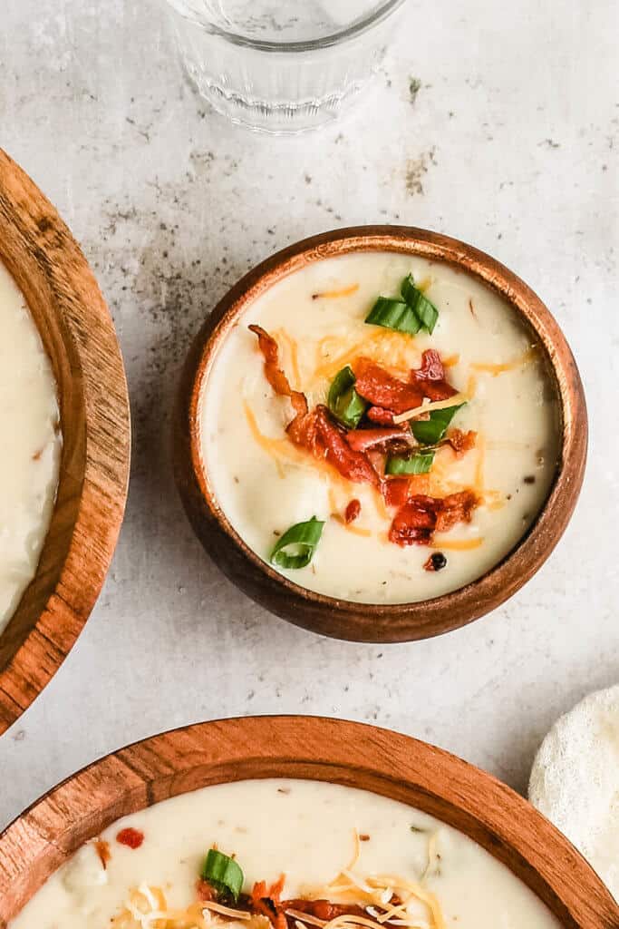 a close up shop of a small wood bowl of baked potato soup