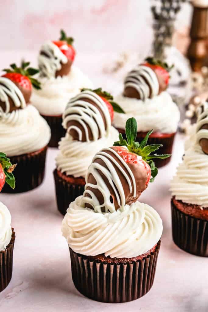 gluten free cupcakes with white buttercream icing and a chocolate covered strawberries on top