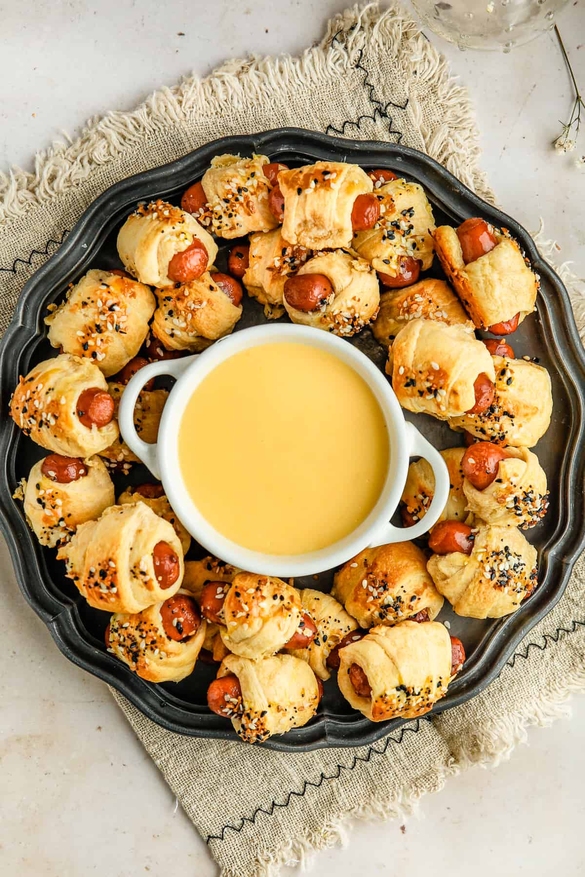 Seasoned Pigs In a Blanket on a large platter with homemade cheese sauce in the middle