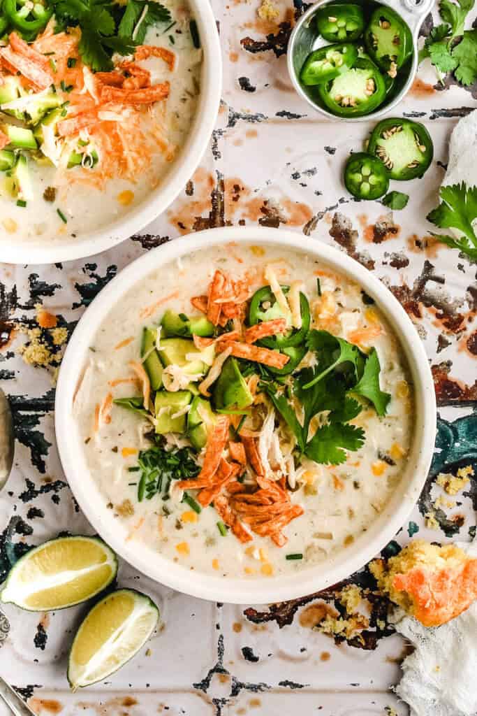 close up of a white bowl filled with cream cheese white chicken chili and toppings