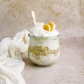 a jar of protein overnight oats with banana cream pie topping with a silver spoon
