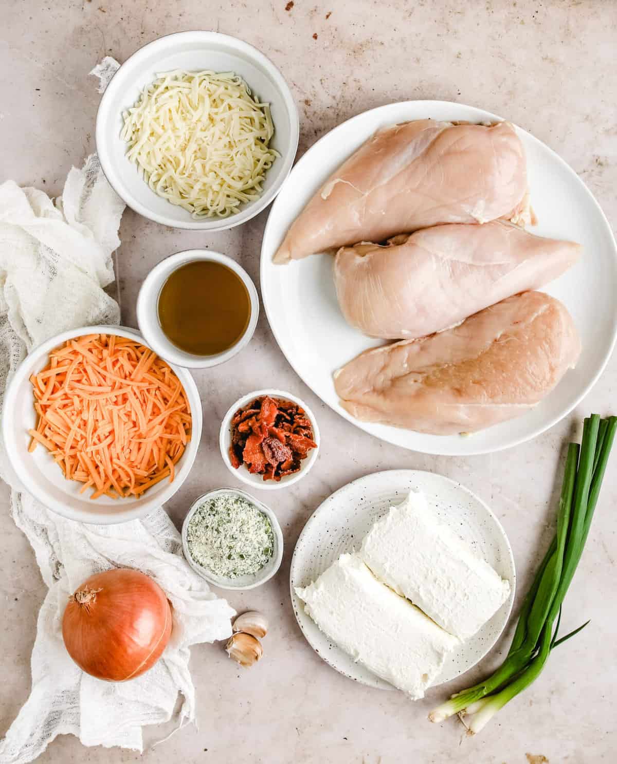 all of the ingredients for the crockpot ranch chicken, chicken breast, bacon, green onions, chicken broth, shredded cheese, green onions, and ranch seasoning