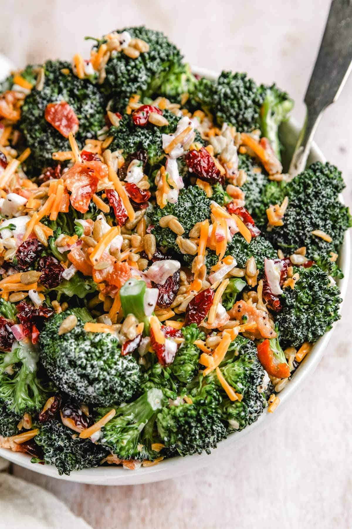 a close up photo of the creamy broccoli salad in a large serving bowl