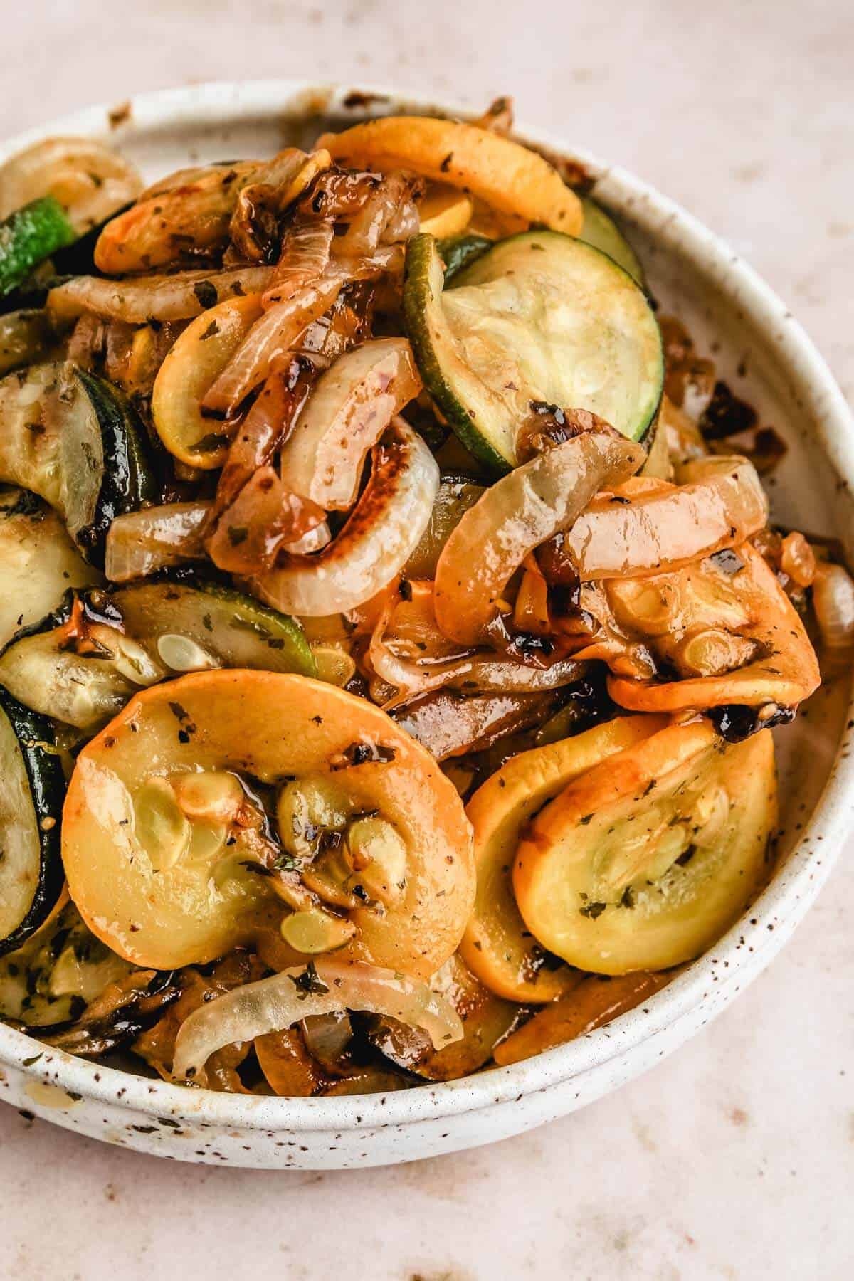 an up close shot of a bowl filled with sautéed zucchini and onions