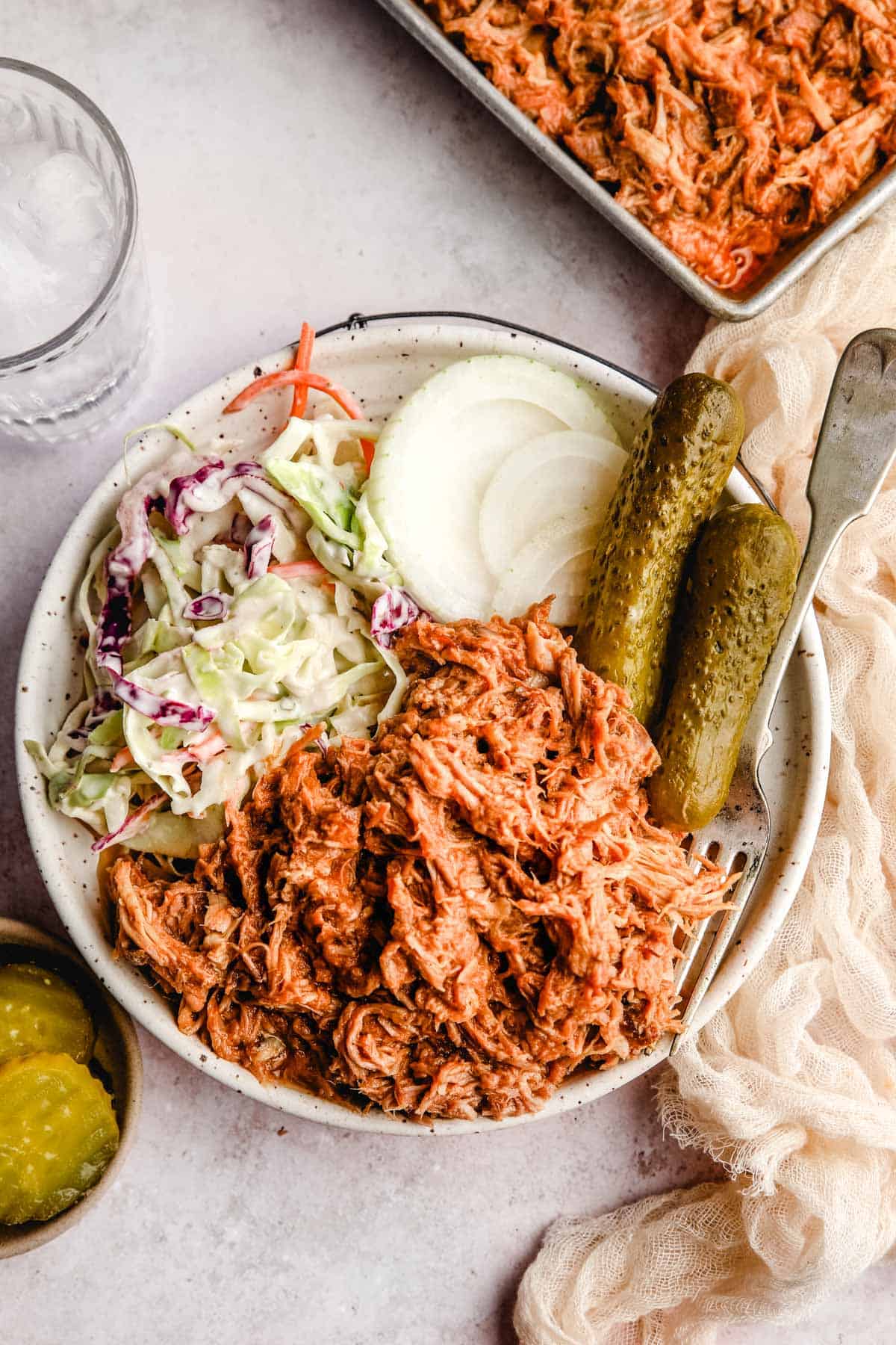 Crockpot Pulled Pork in a plate with coleslaw, pickles, and onions
