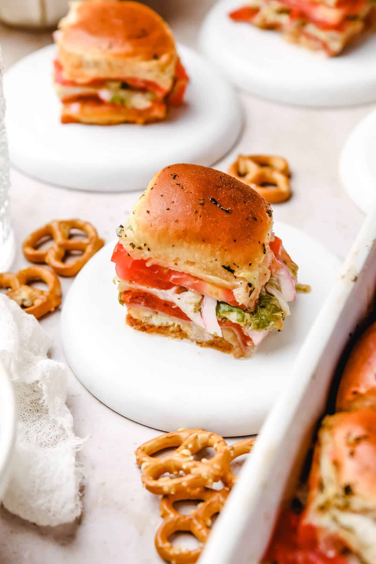 a closeup of a grinder sandwich slider on a white plate, and one in the background