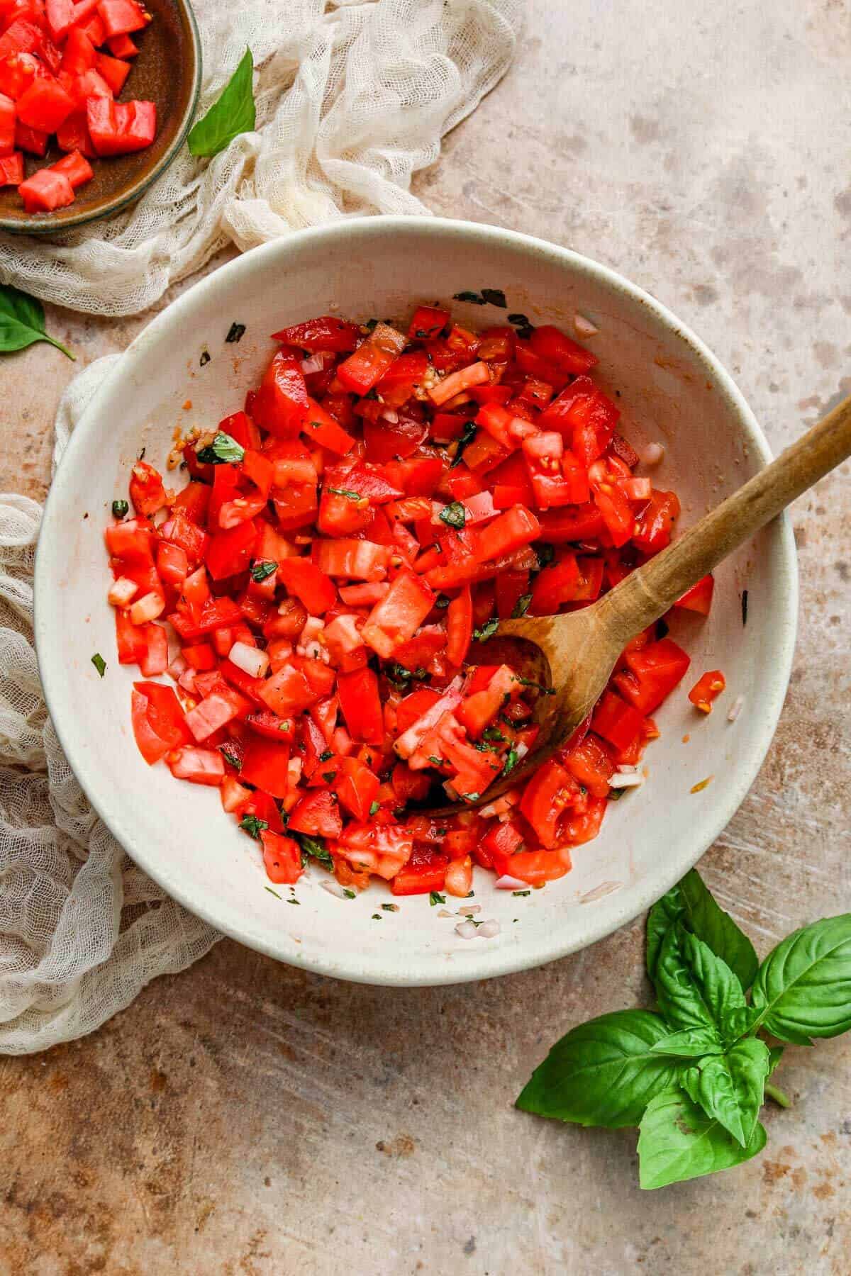 a bowl of diced tomatoes mixed with basil, olive oil, and balsamic vinegar