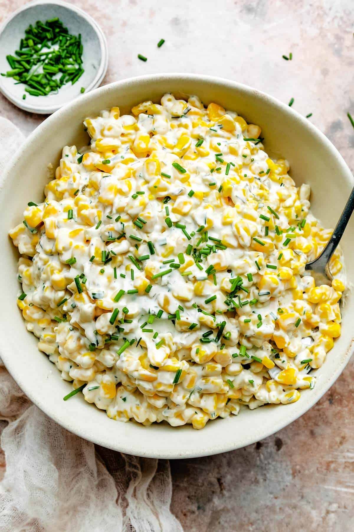 an overhead shot of a bowl of cream cheese corn dip made with frozen corn and chive and onion cream cheese. 